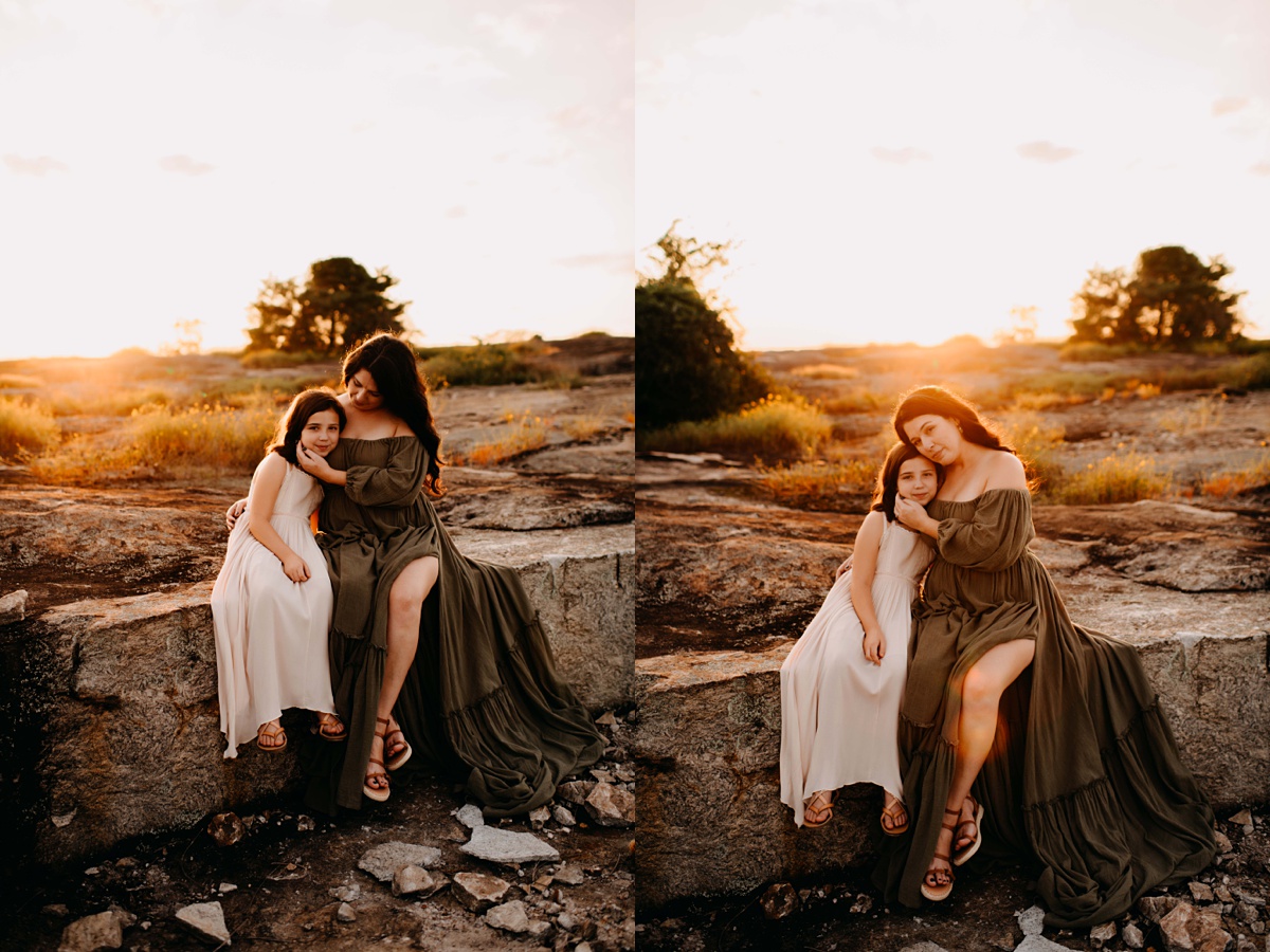 Mother sitting on a rock with her daughter at golden hour. 