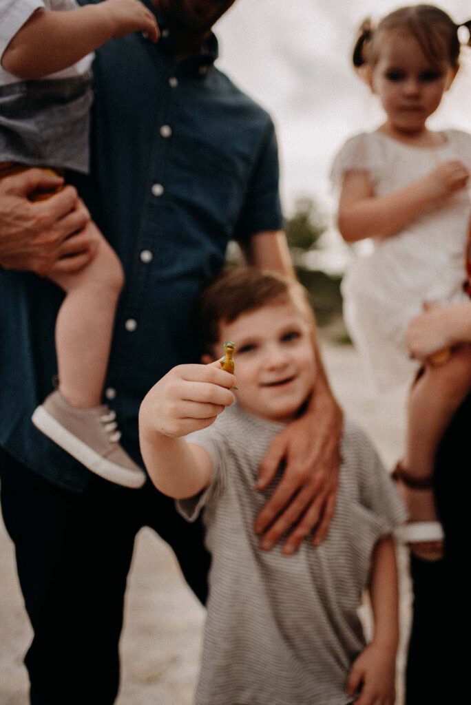 Autistic little boy showing off his dino toy at his family photo session.