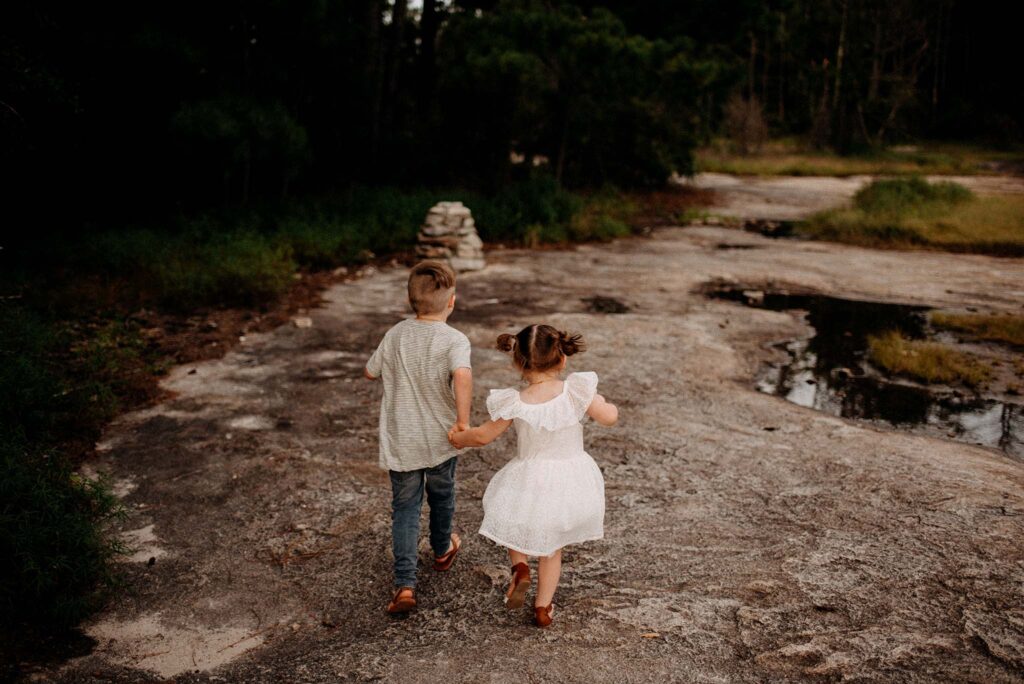 Siblings holding hands during a hike at arabia mountain park for a family photo session. 