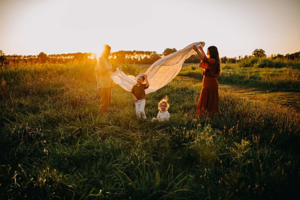 Family playing on a blanket in the sunset light photographed by a GA photographer.