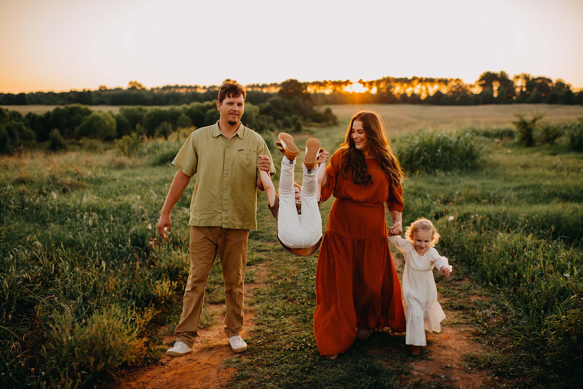 Family walking and swinging their son in the sunset photographed by a Hampton, ga photographer.